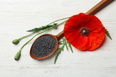 Flat lay composition with poppy seeds and flower on wooden table