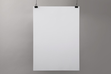 Photo of White blank poster hanging near grey wall