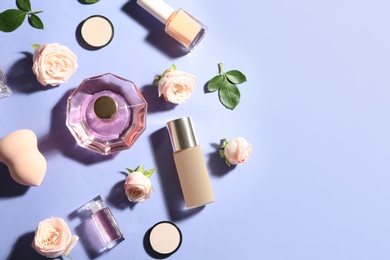Flat lay composition with bottles of perfume, cosmetics and roses on color background. Space for text