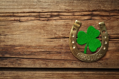 Decorative clover leaf and horseshoe on wooden background, flat lay with space for text. St. Patrick's Day celebration