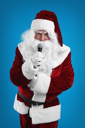 Photo of Santa Claus singing with microphone on blue background. Christmas music