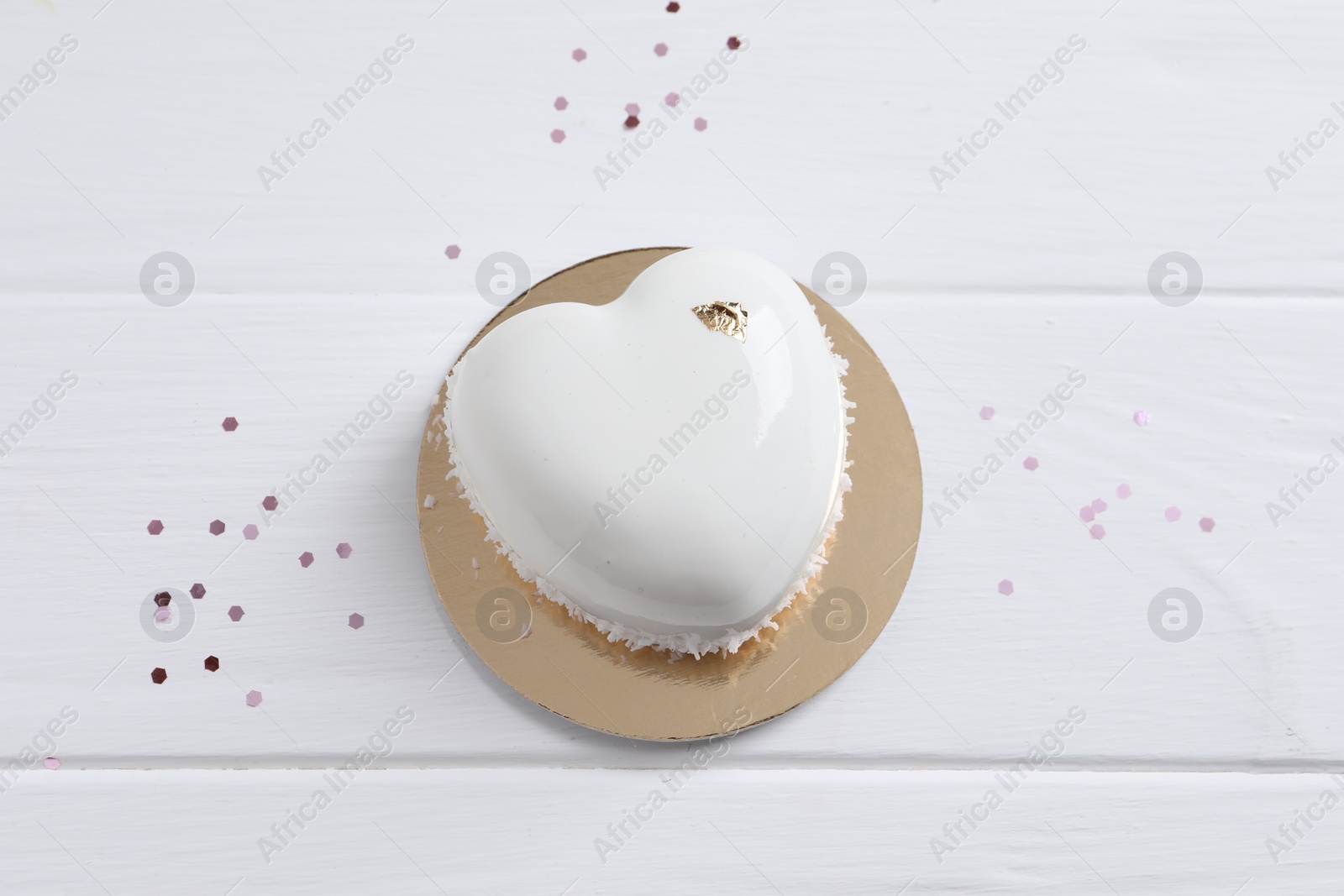 Photo of St. Valentine's Day. Delicious heart shaped cake and confetti on white wooden table, top view