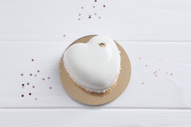 Photo of St. Valentine's Day. Delicious heart shaped cake and confetti on white wooden table, top view