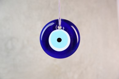 Photo of Evil eye amulet hanging on light background, closeup