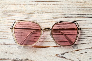 Photo of New stylish sunglasses on white wooden table, top view