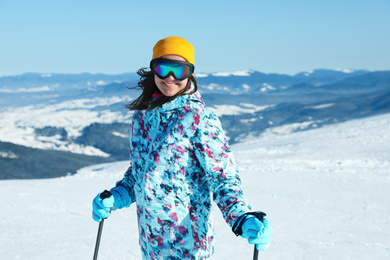 Photo of Female skier on snowy slope in mountains. Winter vacation