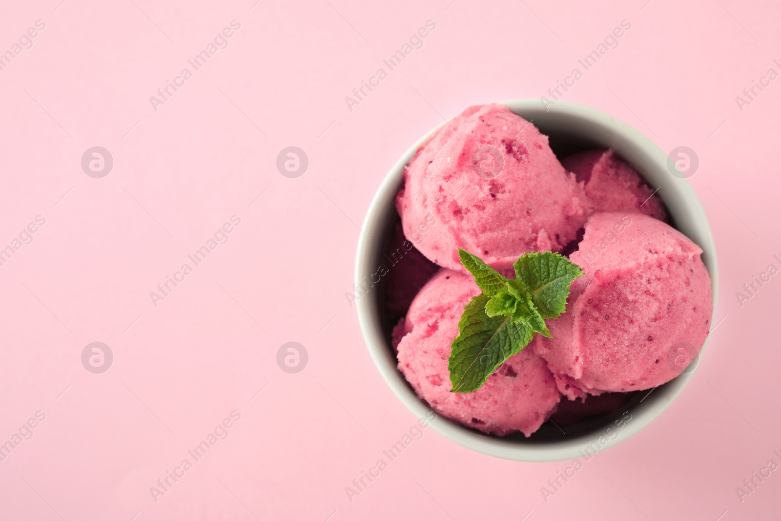 Photo of Delicious strawberry ice cream with mint in dessert bowl on pink background, top view. Space for text