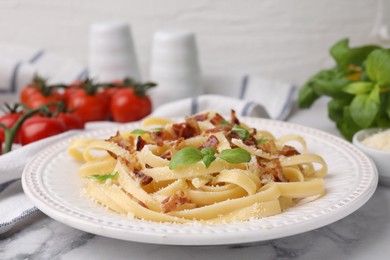 Photo of Tasty pasta with bacon and basil on white marble table, closeup