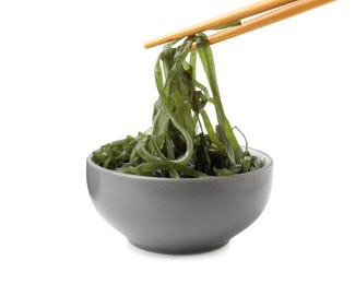 Photo of Taking tasty seaweed salad from bowl on white background
