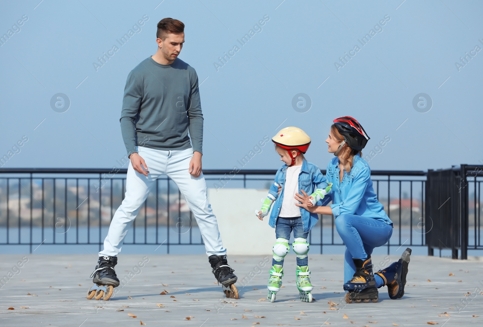 Photo of Happy family roller skating on embankment. Active leisure