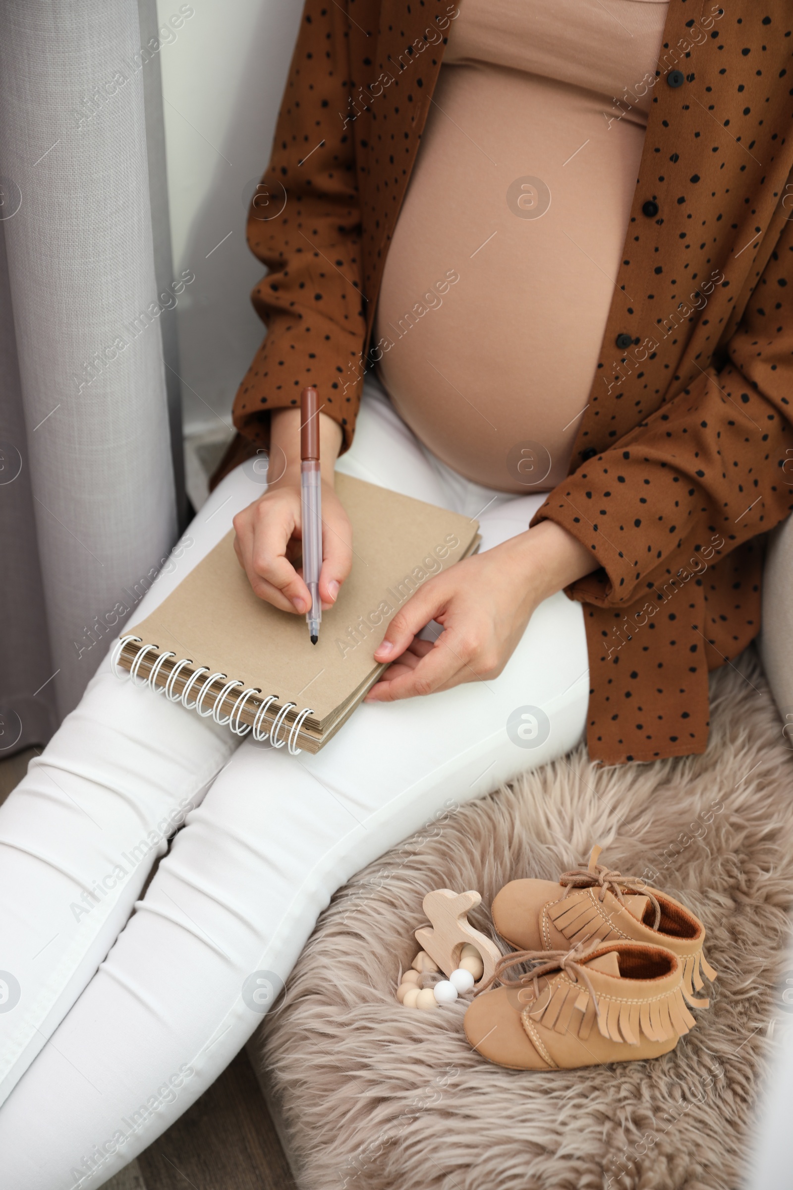 Photo of Pregnant woman writing baby names list at home, closeup