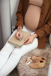 Photo of Pregnant woman writing baby names list at home, closeup