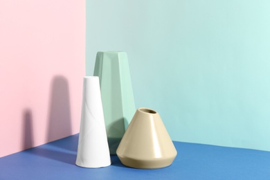 Stylish empty ceramic vases on color background