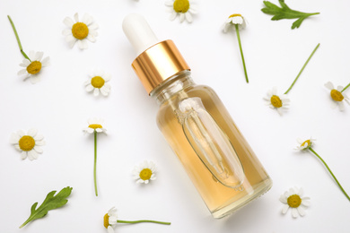 Photo of Composition with chamomile flowers and bottle of essential oil on white background, top view