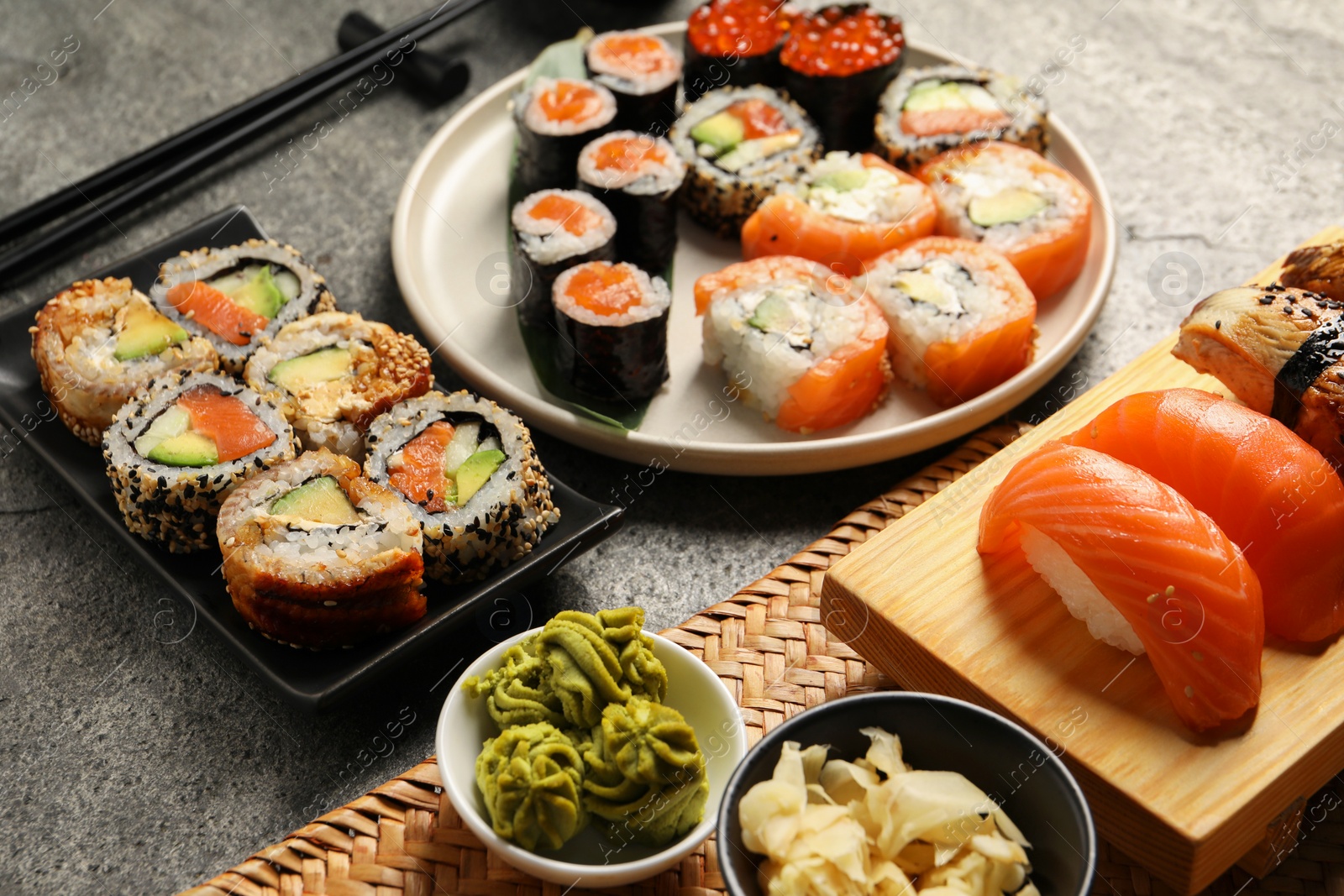Photo of Different tasty sushi rolls on grey table