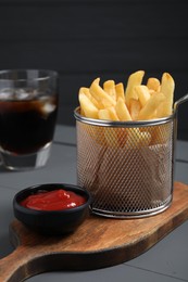 Photo of Tasty French fries and ketchup on grey wooden table