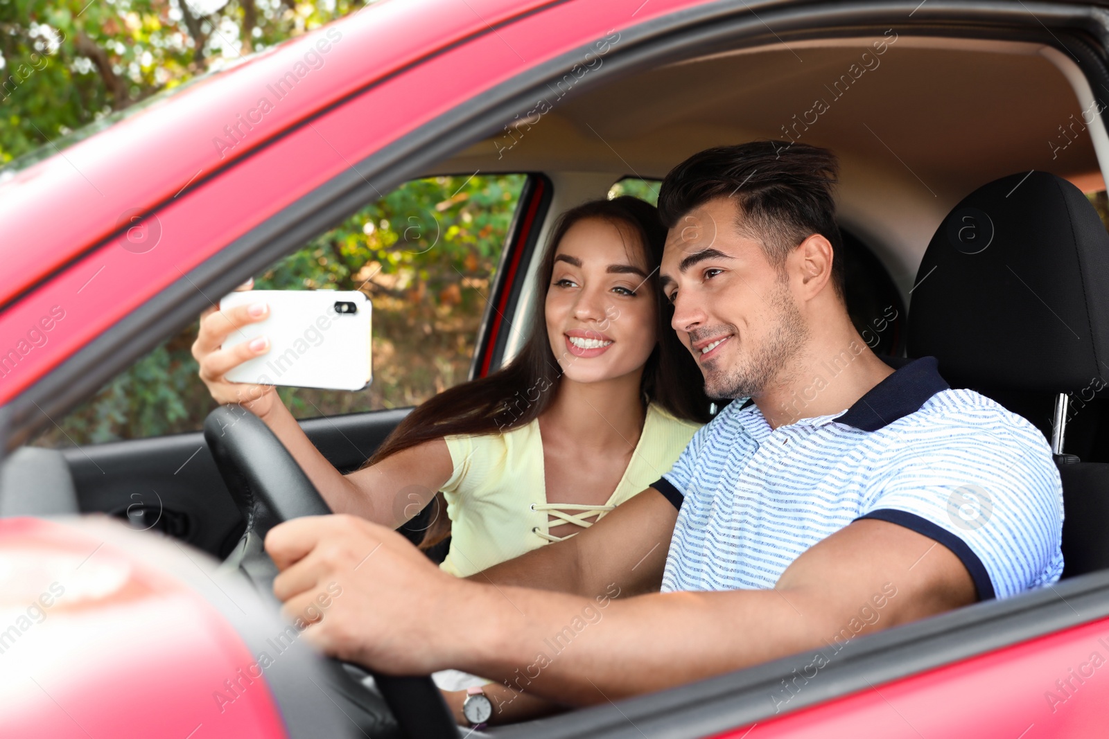 Photo of Happy young couple taking selfie in car on road trip