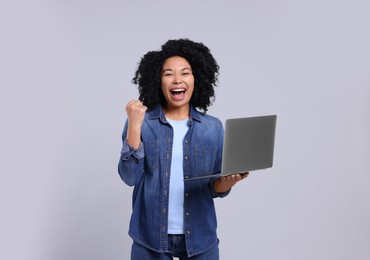 Photo of Emotional young woman with laptop on light grey background