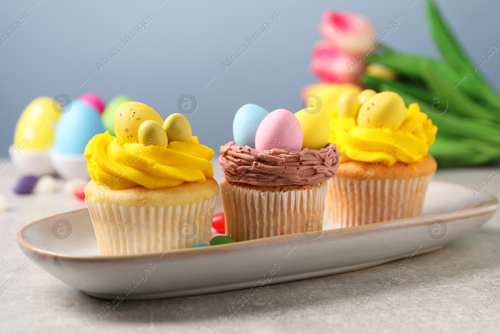 Photo of Tasty decorated Easter cupcakes on grey table, closeup