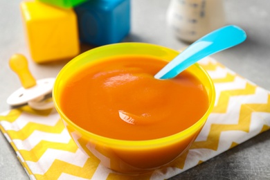 Photo of Bowl of healthy baby food on grey table, closeup