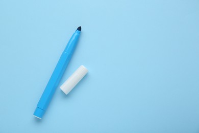 Photo of Bright marker and cap on light blue background, flat lay. Space for text