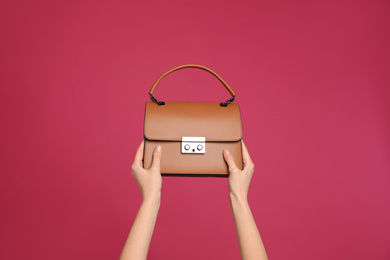 Woman holding stylish handbag on pink background, closeup