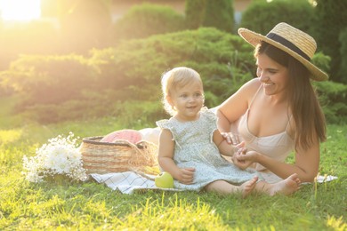 Photo of Mother with her baby daughter having picnic in garden on sunny day