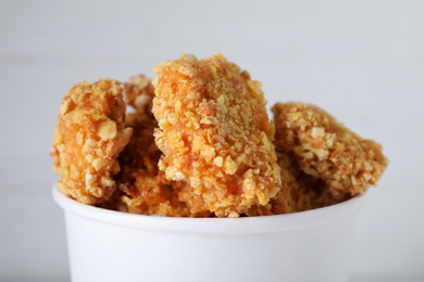 Photo of Bucket with yummy nuggets on light background, closeup