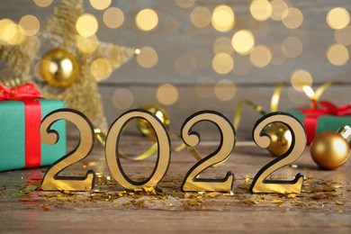 Photo of Number 2022 and festive decor on wooden table, bokeh effect. Happy New Year