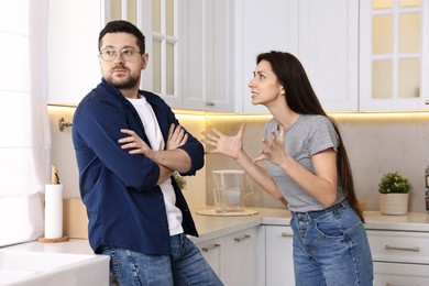 Photo of Annoyed wife screaming at her husband in kitchen. Relationship problems
