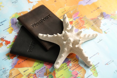 Passports and sea star on world map, closeup. Travel agency