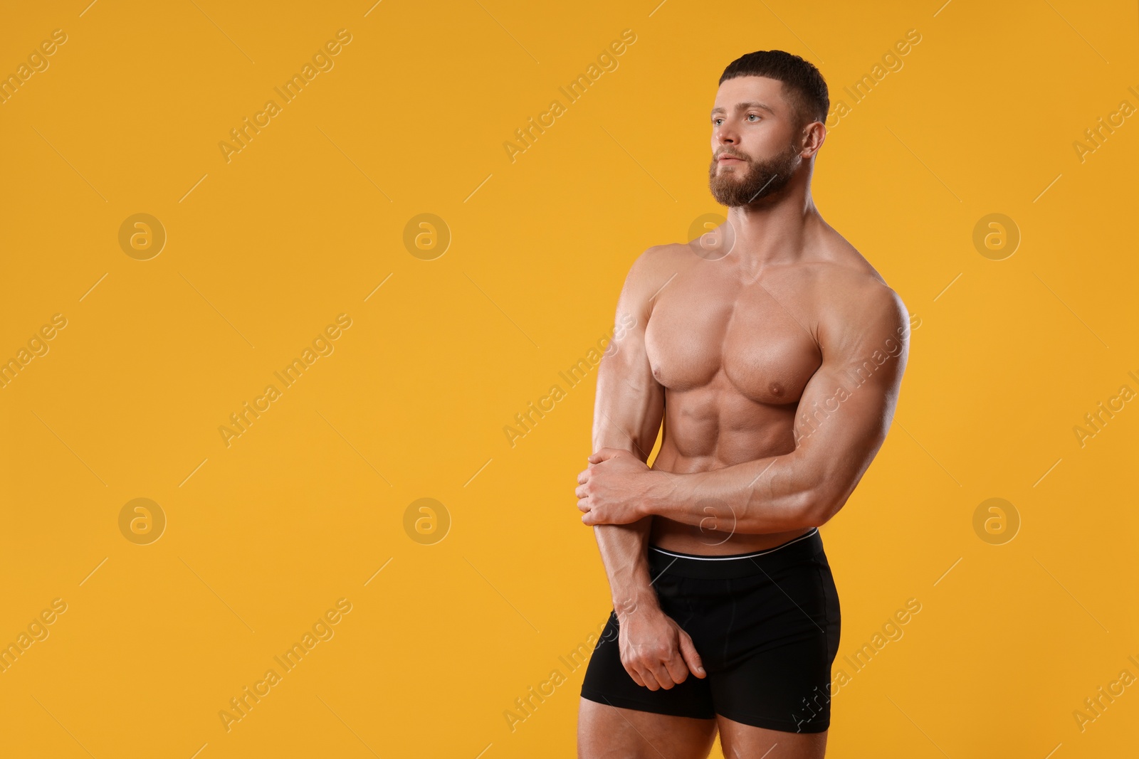 Photo of Young man is stylish black underwear on orange background. Space for text