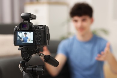 Photo of Teenage blogger explaining something while streaming at home, focus on camera