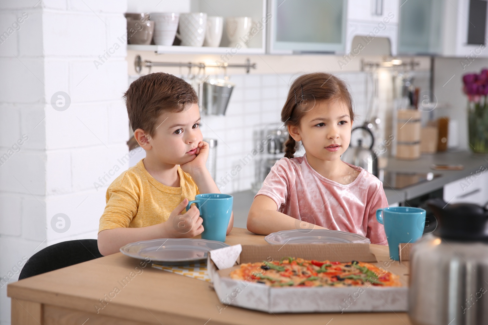 Photo of Cute little kids eating tasty pizza at home