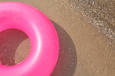 Photo of Bright inflatable ring near sea on sunny day. Space for text