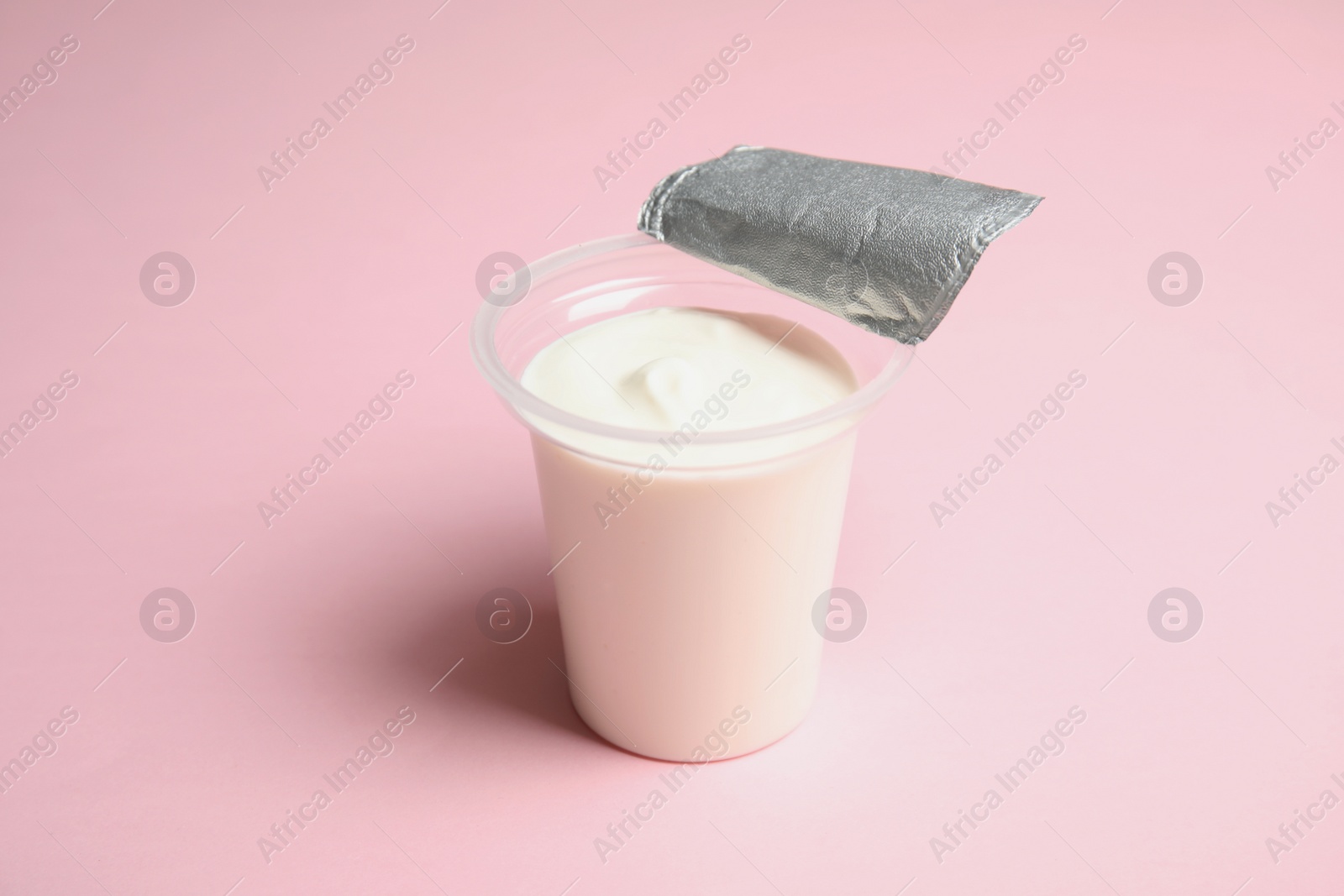 Photo of Plastic cup with creamy yogurt on color background