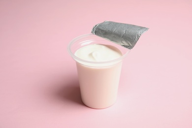 Plastic cup with creamy yogurt on color background