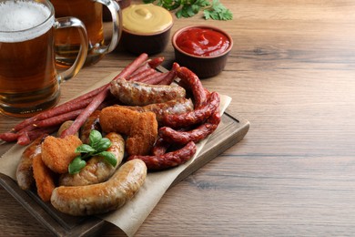 Photo of Set of different tasty snacks and beer on wooden table, space for text