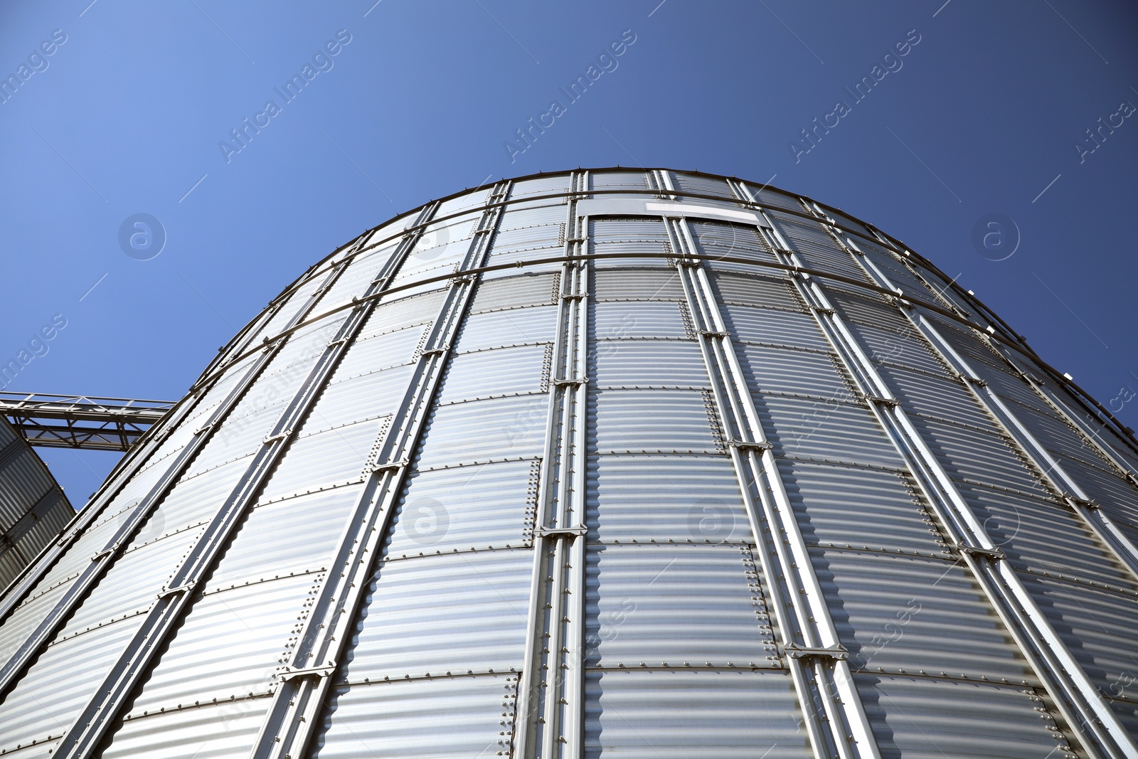 Photo of Modern granary for storing cereal grains against blue sky, low angle view
