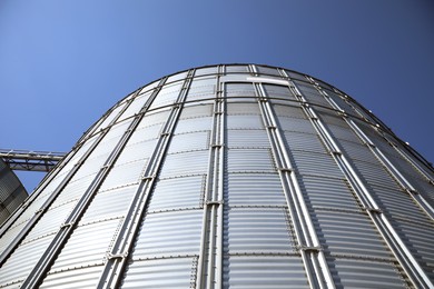 Photo of Modern granary for storing cereal grains against blue sky, low angle view