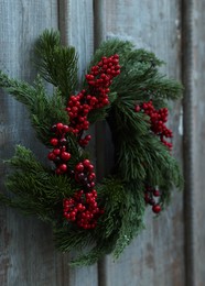 Photo of Beautiful Christmas wreath with red berries hanging on wooden wall