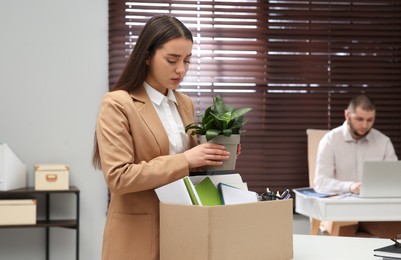 Dismissed woman packing personal stuff into box in office