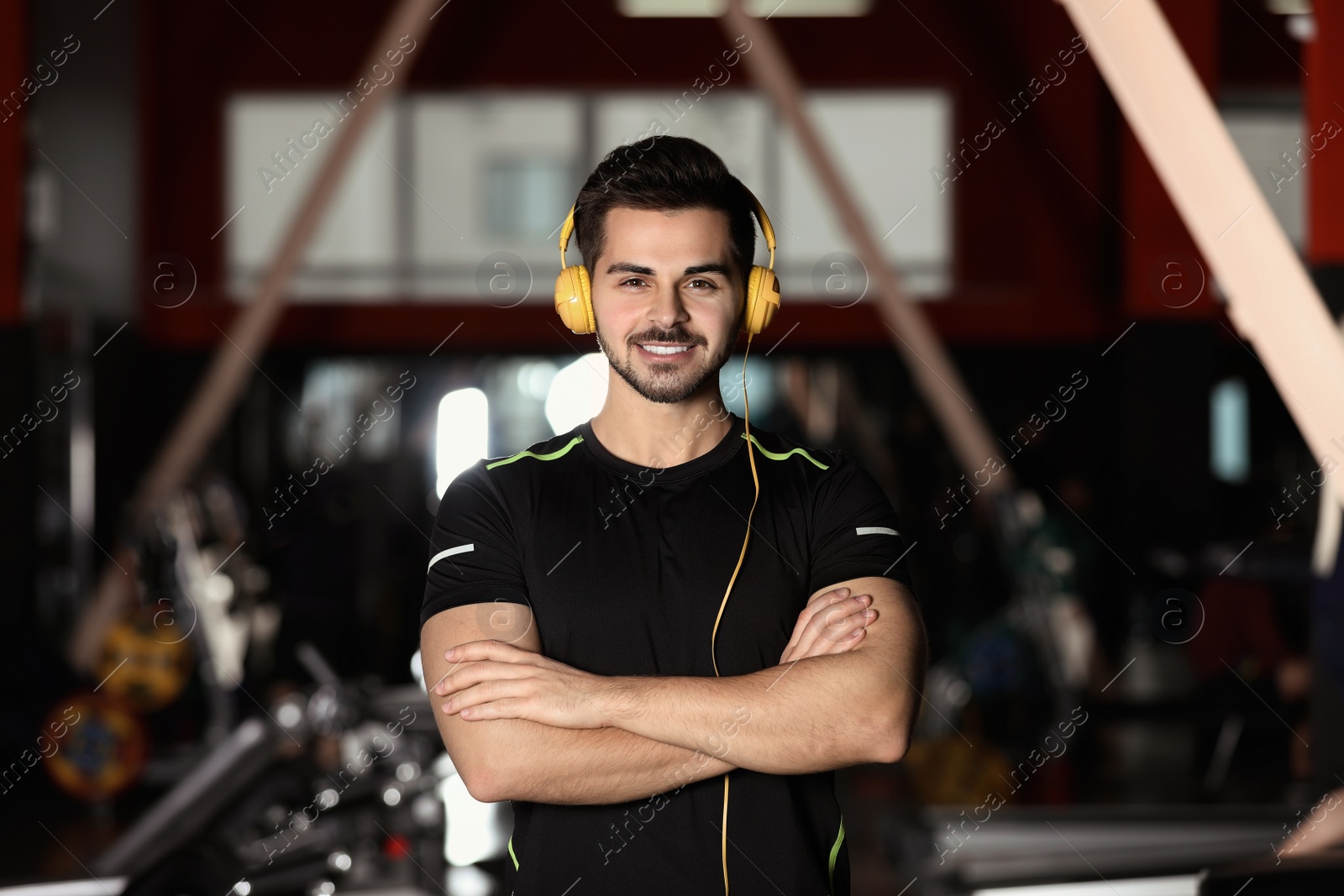 Photo of Young man listening to music with headphones at gym