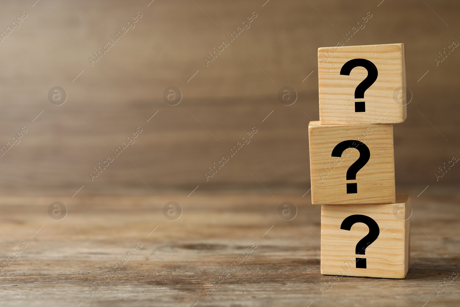 Photo of Cubes with question marks on wooden background, closeup. Space for text