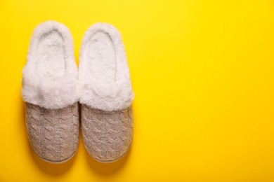 Pair of beautiful soft slippers on yellow background, top view. Space for text