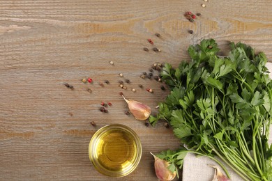 Bunch of raw parsley, oil, garlic and peppercorns on wooden table, flat lay. Space for text