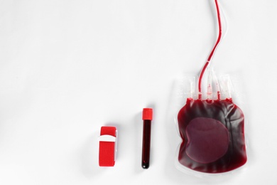 Photo of Blood pack for transfusion and test tube on white background, top view. Donation day
