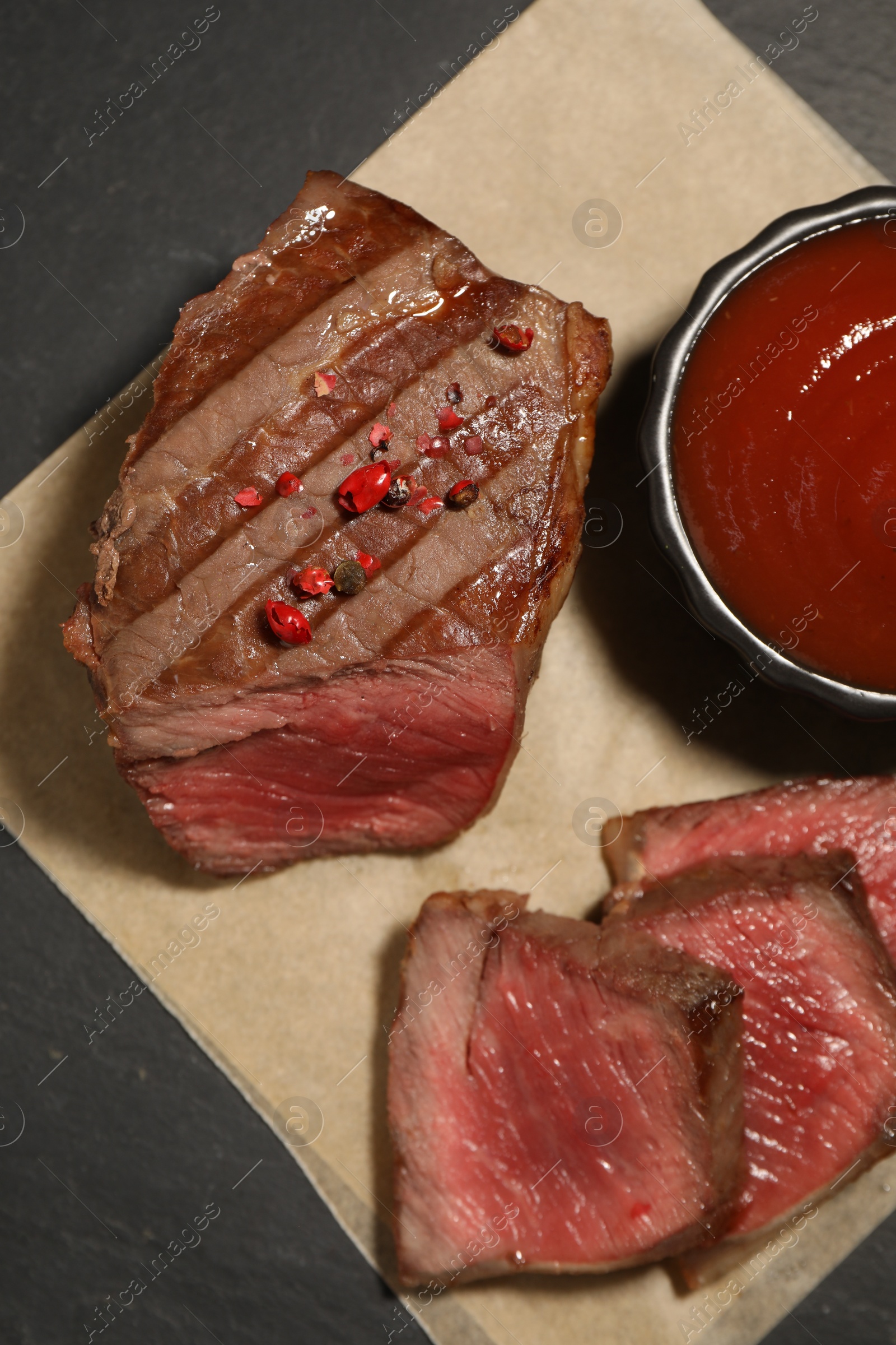 Photo of Delicious grilled beef steak with spices and tomato sauce on table, top view