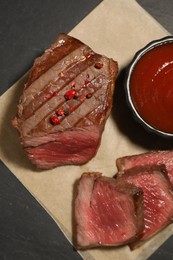 Delicious grilled beef steak with spices and tomato sauce on table, top view