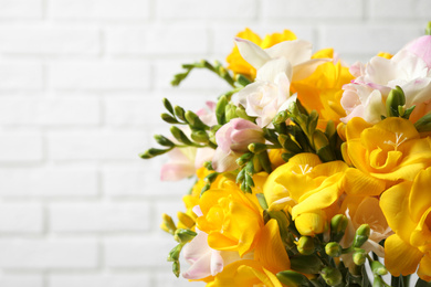 Beautiful blooming freesias against white brick wall